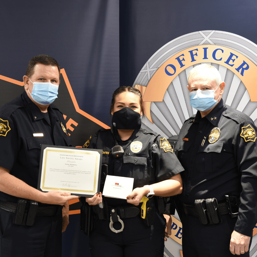 Three police officers in masks holding an award