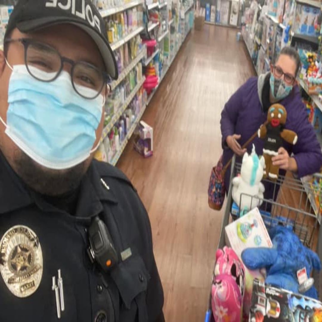 police officer and woman in mask holding a gingerbread stuffed animal