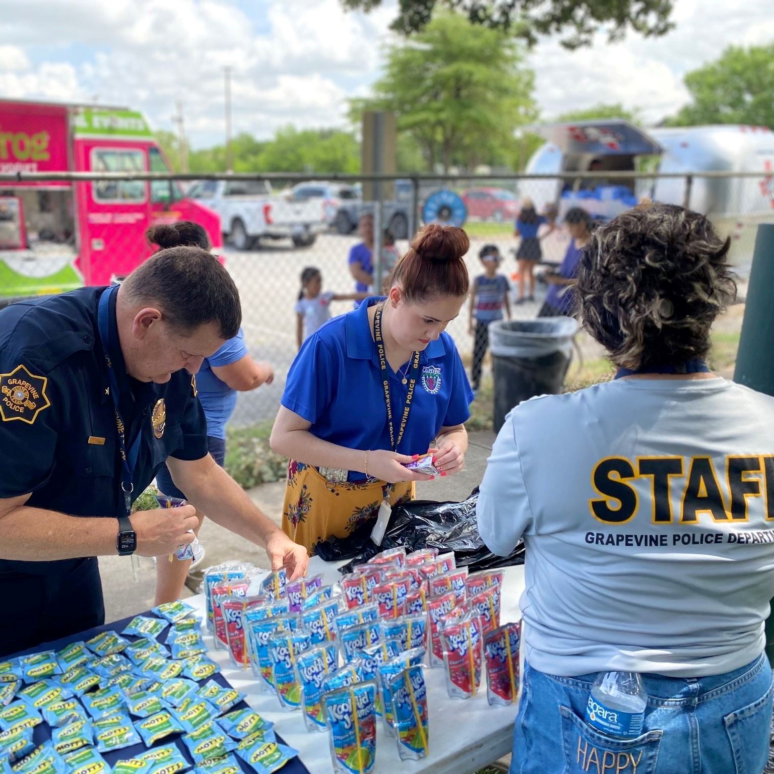 police and outreach staff serving lunches at picnic table